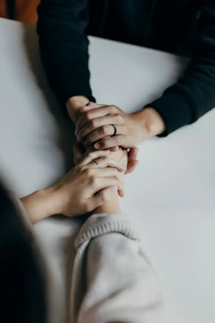 One person gently supporting another person's hands